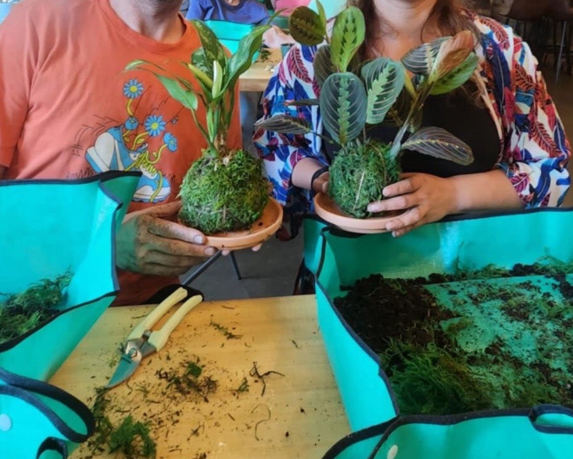 Two people holding plants with a table of plants in the background, featuring 'florasoulhorticulture' logo.